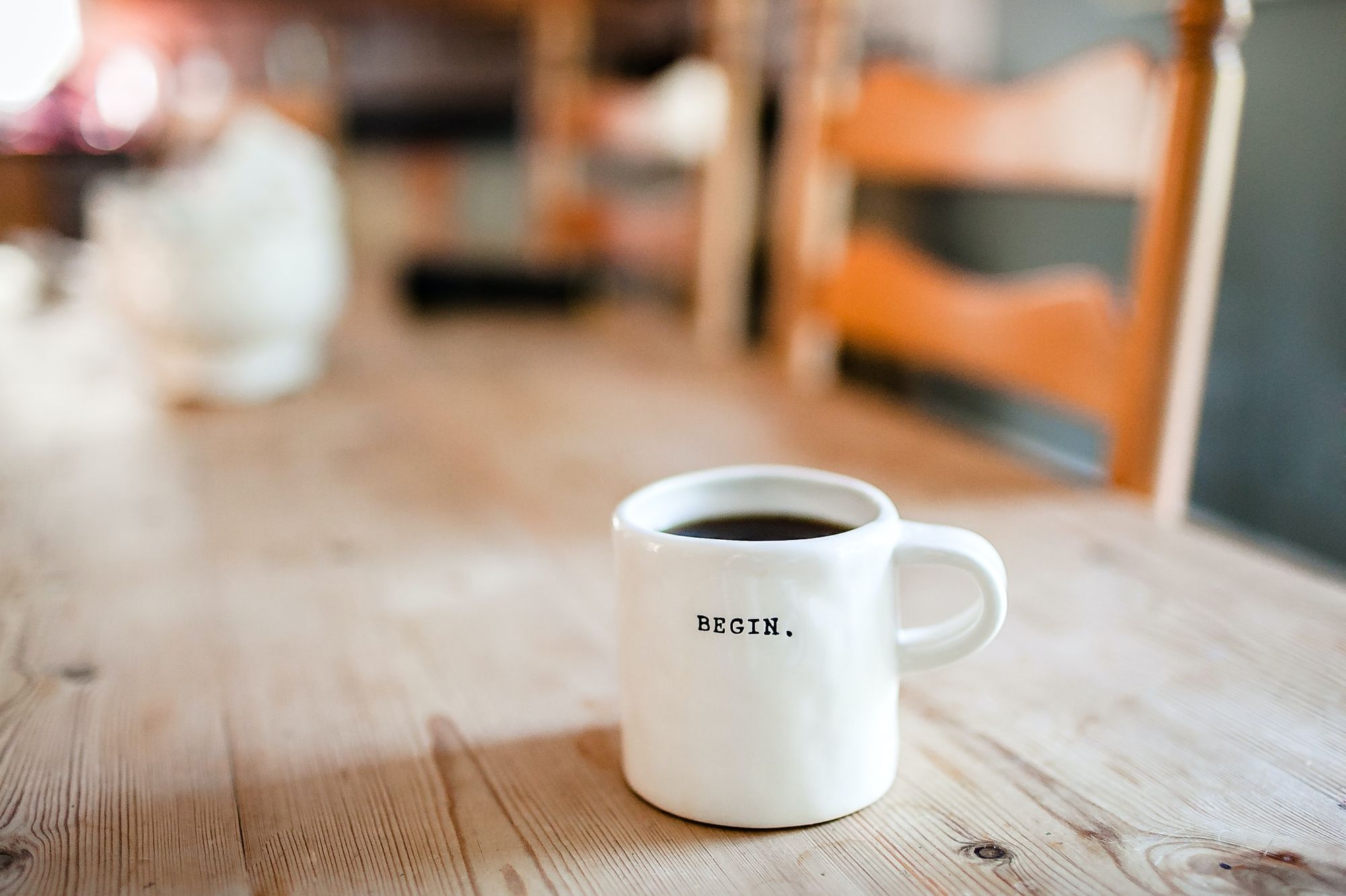 A full white coffee mug with the word Begin printed on it.
