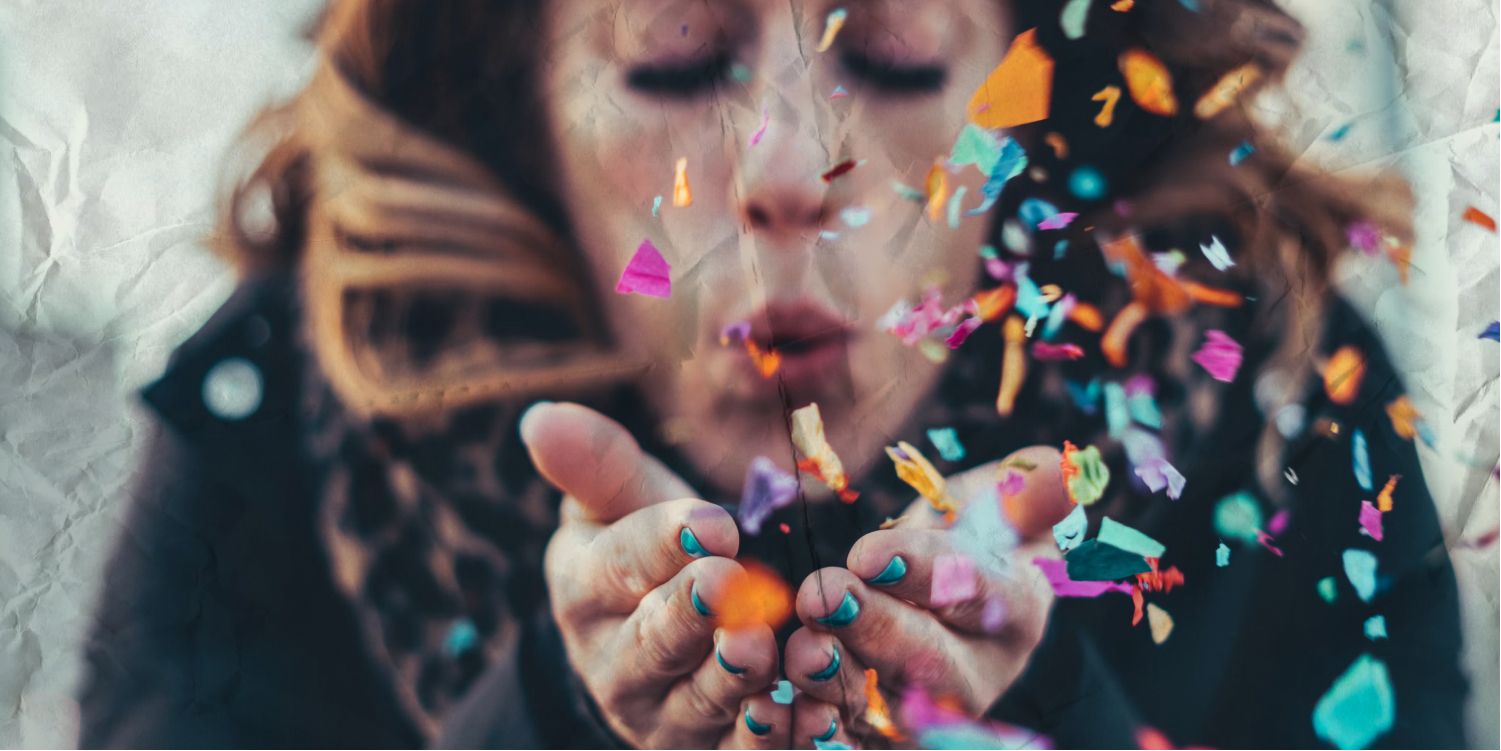 Woman blowing confetti from her hands