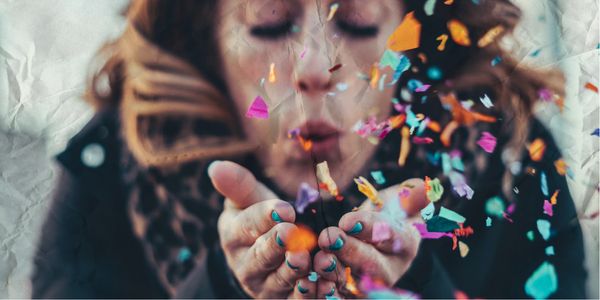 Woman blowing confetti from her hands